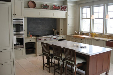 Enclosed kitchen - mid-sized traditional l-shaped travertine floor enclosed kitchen idea in Portland Maine with a farmhouse sink, shaker cabinets, white cabinets, marble countertops, gray backsplash, stone tile backsplash, stainless steel appliances and an island