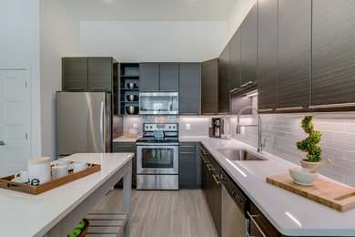 Minimalist laminate floor and gray floor kitchen photo in DC Metro with an undermount sink, flat-panel cabinets, quartz countertops, gray backsplash, stainless steel appliances, an island and white countertops
