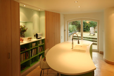 ロンドンにあるモダンスタイルのおしゃれなアイランドキッチン (一体型シンク、フラットパネル扉のキャビネット、淡色木目調キャビネット、ガラス板のキッチンパネル、コンクリートの床) の写真