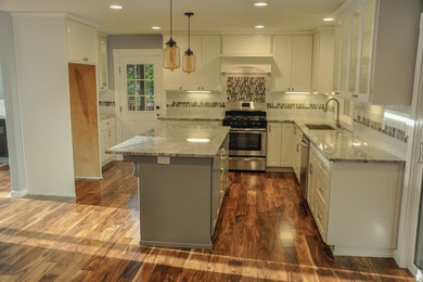 Kitchen - contemporary medium tone wood floor kitchen idea in Portland with an undermount sink, shaker cabinets, white cabinets, granite countertops, glass tile backsplash, stainless steel appliances and an island