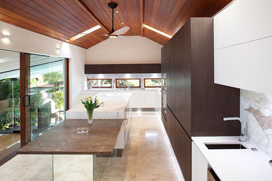 This is an example of a large modern single-wall open plan kitchen in Sydney with a single-bowl sink, flat-panel cabinets, dark wood cabinets, marble worktops, multi-coloured splashback, mirror splashback, stainless steel appliances, travertine flooring and multiple islands.