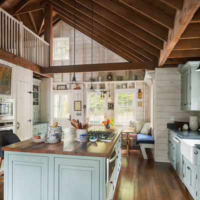 Example of a large mountain style dark wood floor eat-in kitchen design in New York with a farmhouse sink, raised-panel cabinets, blue cabinets, granite countertops, stainless steel appliances and an island