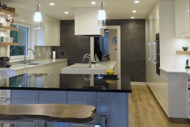 Foto på ett funkis u-kök, med en undermonterad diskho, släta luckor, vita skåp, bänkskiva i kvartsit, vitt stänkskydd, ljust trägolv och flera köksöar