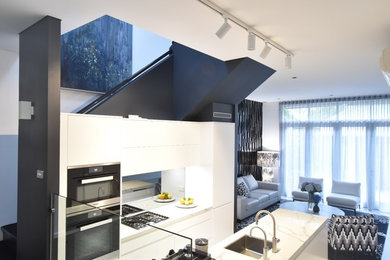 На фото: большая кухня-гостиная в стиле ретро с зеркальным фартуком, техникой из нержавеющей стали, мраморным полом и островом