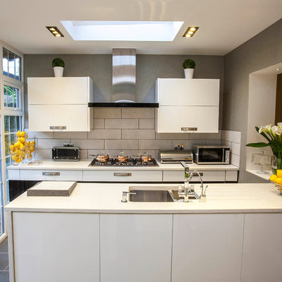 Inspiration for a small contemporary galley kitchen remodel in London with a double-bowl sink, flat-panel cabinets, white cabinets, white backsplash, subway tile backsplash and a peninsula