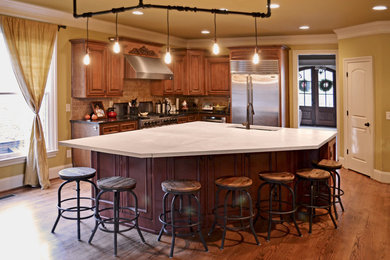 Cette photo montre une cuisine américaine chic en L et bois brun de taille moyenne avec un évier encastré, un plan de travail en béton, une crédence beige, un électroménager en acier inoxydable, un sol en bois brun et îlot.