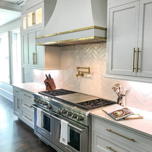 Esempio di un ampio cucina con isola centrale classico con lavello stile country, ante bianche, top in quarzo composito, paraspruzzi bianco, paraspruzzi con piastrelle in ceramica, elettrodomestici in acciaio inossidabile, parquet scuro, pavimento marrone, top bianco e ante con riquadro incassato