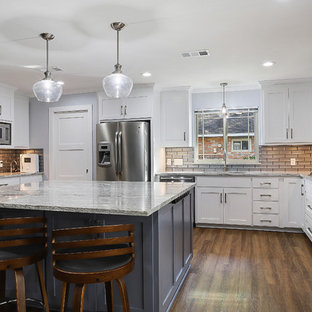Large transitional open concept kitchen designs - Open concept kitchen - large transitional u-shaped vinyl floor and brown floor open concept kitchen idea in New Orleans with a single-bowl sink, shaker cabinets, white cabinets, granite countertops, gray backsplash, glass tile backsplash, stainless steel appliances, an island and white countertops
