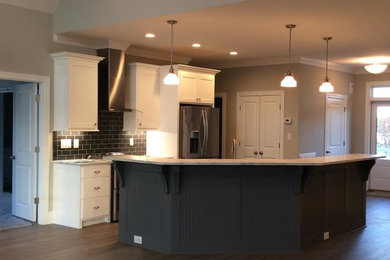 Inspiration for a mid-sized transitional dark wood floor and brown floor open concept kitchen remodel in Charlotte with shaker cabinets, white cabinets, granite countertops, black backsplash, subway tile backsplash, stainless steel appliances and an island