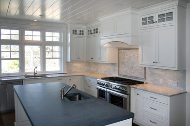 Example of a beach style kitchen design in Boston with brown backsplash and an island