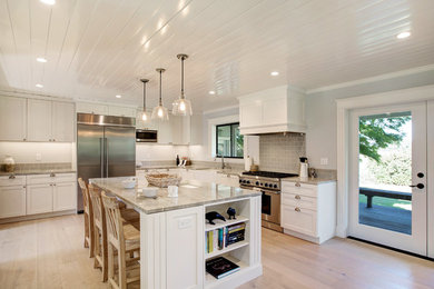 Inspiration for a mid-sized timeless l-shaped light wood floor and beige floor eat-in kitchen remodel in San Francisco with a farmhouse sink, shaker cabinets, white cabinets, quartzite countertops, green backsplash, subway tile backsplash, stainless steel appliances, an island and green countertops