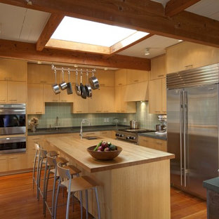 1950s l-shaped enclosed kitchen photo in Boston with flat-panel cabinets, medium tone wood cabinets, wood countertops, green backsplash and stainless steel appliances