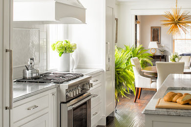ポートランド(メイン)にある中くらいなトラディショナルスタイルのおしゃれなキッチン (落し込みパネル扉のキャビネット、白いキャビネット、大理石カウンター、白いキッチンパネル、セラミックタイルのキッチンパネル、シルバーの調理設備、濃色無垢フローリング) の写真