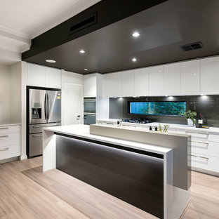 Photo of a large contemporary galley open plan kitchen in Perth with flat-panel cabinets, white cabinets, quartz benchtops, black splashback, window splashback, stainless steel appliances, light hardwood floors, multiple islands, brown floor and white benchtop.
