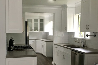 ロサンゼルスにあるトランジショナルスタイルのおしゃれなキッチン (白いキャビネット、クオーツストーンカウンター、白いキッチンパネル、サブウェイタイルのキッチンパネル、シルバーの調理設備) の写真