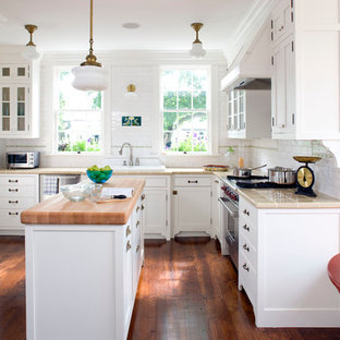 Inspiration for a mid-sized country u-shaped kitchen in Boston with a drop-in sink, shaker cabinets, white cabinets, white splashback, subway tile splashback, stainless steel appliances, with island, tile benchtops, dark hardwood floors and brown floor.