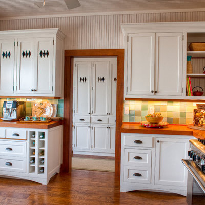 Mid-sized island style galley dark wood floor and brown floor eat-in kitchen photo in Miami with wood countertops, green backsplash, a farmhouse sink, shaker cabinets, white cabinets, glass tile backsplash and no island