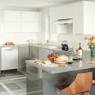 Mid-sized transitional open concept kitchen pictures - Example of a mid-sized transitional u-shaped gray floor open concept kitchen design in Portland Maine with flat-panel cabinets, stainless steel cabinets, a peninsula, white backsplash and stainless steel appliances