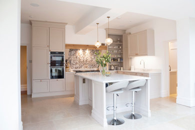 Medium sized traditional l-shaped kitchen in Cardiff with a submerged sink, shaker cabinets, beige cabinets, composite countertops, grey splashback, stainless steel appliances, porcelain flooring, an island, beige floors and white worktops.