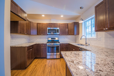 Eat-in kitchen - mid-sized transitional u-shaped laminate floor and brown floor eat-in kitchen idea in Other with an undermount sink, shaker cabinets, dark wood cabinets, white backsplash, ceramic backsplash, stainless steel appliances and granite countertops