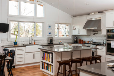 Eat-in kitchen - large transitional u-shaped medium tone wood floor and brown floor eat-in kitchen idea in Denver with a farmhouse sink, shaker cabinets, quartz countertops, white backsplash, subway tile backsplash, stainless steel appliances, an island and white cabinets
