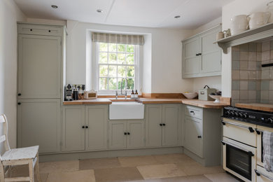 На фото: кухня в стиле кантри с фасадами в стиле шейкер, деревянной столешницей и полом из керамической плитки