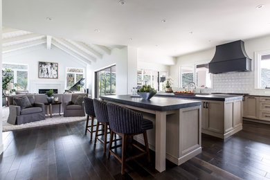 Inspiration for a large farmhouse u-shaped dark wood floor and brown floor open concept kitchen remodel in San Diego with an undermount sink, shaker cabinets, beige cabinets, soapstone countertops, white backsplash, ceramic backsplash and an island