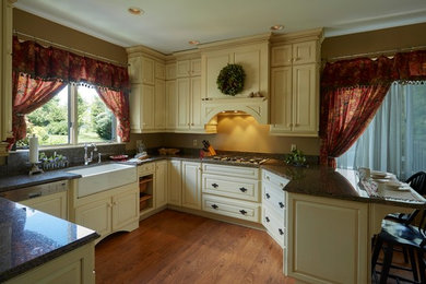 Eat-in kitchen - mid-sized country u-shaped medium tone wood floor and brown floor eat-in kitchen idea in Baltimore with a farmhouse sink, raised-panel cabinets, beige cabinets, granite countertops and paneled appliances