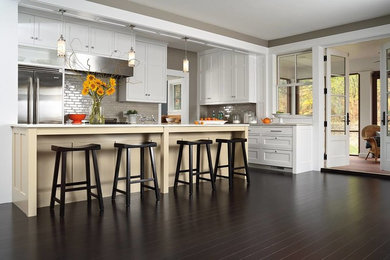 Example of a mid-sized transitional l-shaped dark wood floor open concept kitchen design in San Francisco with beaded inset cabinets, white cabinets, beige backsplash, subway tile backsplash, stainless steel appliances and a peninsula