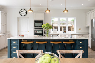 Design ideas for a traditional u-shaped kitchen in Hertfordshire with quartz worktops, white worktops, a belfast sink, beaded cabinets, grey cabinets, stainless steel appliances, an island and grey floors.