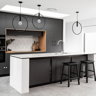 Inspiration for a modern galley kitchen in Hobart with with island, a double-bowl sink, flat-panel cabinets, black cabinets, white splashback, panelled appliances, concrete floors, grey floor and white benchtop.