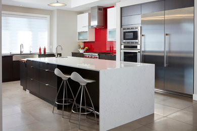 Large trendy l-shaped travertine floor kitchen photo in Toronto with a farmhouse sink, flat-panel cabinets, quartz countertops, red backsplash, glass sheet backsplash, stainless steel appliances, an island and dark wood cabinets