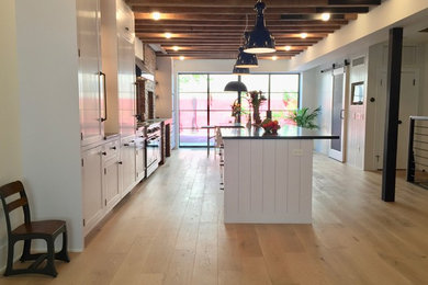 This is an example of a kitchen/diner in Other with shaker cabinets, white cabinets and an island.