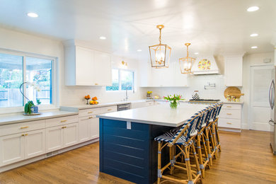 サクラメントにある高級な広いエクレクティックスタイルのおしゃれなキッチン (エプロンフロントシンク、シェーカースタイル扉のキャビネット、白いキャビネット、クオーツストーンカウンター、白いキッチンパネル、サブウェイタイルのキッチンパネル、カラー調理設備、無垢フローリング、茶色い床、白いキッチンカウンター) の写真