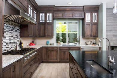 Example of a large transitional l-shaped porcelain tile open concept kitchen design in San Diego with an undermount sink, recessed-panel cabinets, dark wood cabinets, quartz countertops, gray backsplash, glass sheet backsplash, stainless steel appliances and an island