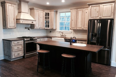 Example of a large transitional l-shaped dark wood floor eat-in kitchen design in Atlanta with a farmhouse sink, raised-panel cabinets, distressed cabinets, wood countertops, stainless steel appliances and an island