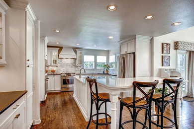 Eat-in kitchen - mid-sized transitional u-shaped medium tone wood floor eat-in kitchen idea in Denver with shaker cabinets, white cabinets, quartz countertops, gray backsplash, stone tile backsplash, stainless steel appliances, an island and an undermount sink
