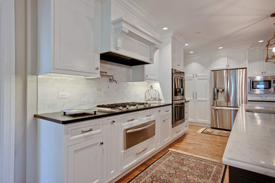 Large elegant u-shaped medium tone wood floor eat-in kitchen photo in Chicago with a double-bowl sink, beaded inset cabinets, white cabinets, quartzite countertops, gray backsplash, stone tile backsplash, stainless steel appliances and an island