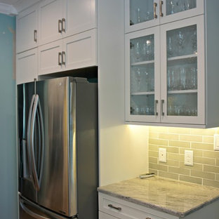 Craftsman kitchen pictures - Example of an arts and crafts medium tone wood floor kitchen design in Raleigh with shaker cabinets, white cabinets, granite countertops, gray backsplash, stainless steel appliances and an island