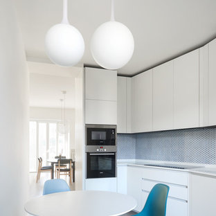 Ispirazione per una cucina abitabile contemporanea con ante lisce, ante bianche e paraspruzzi blu