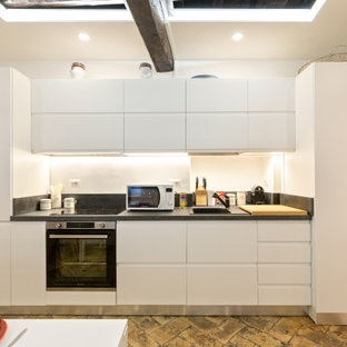 Photo of a small contemporary single-wall eat-in kitchen in Rome with a single-bowl sink, beaded inset cabinets, white cabinets, granite benchtops, grey splashback, granite splashback, black appliances, terra-cotta floors, no island, beige floor and grey benchtop.