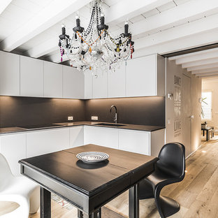 Ispirazione per una cucina minimal di medie dimensioni con lavello sottopiano, ante lisce, ante bianche, paraspruzzi nero, elettrodomestici in acciaio inossidabile, pavimento in legno massello medio, nessuna isola, pavimento marrone e top nero