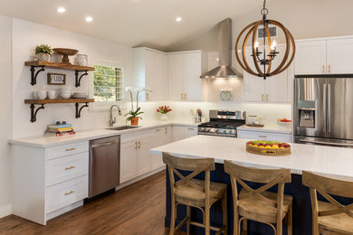 Inspiration for a large contemporary l-shaped dark wood floor and brown floor kitchen remodel in Dallas with an undermount sink, white backsplash, ceramic backsplash, stainless steel appliances, shaker cabinets, white cabinets, solid surface countertops, an island and white countertops