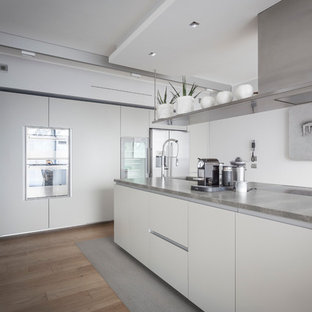 Foto di una grande cucina contemporanea con ante lisce, ante bianche, top in granito, elettrodomestici in acciaio inossidabile, parquet chiaro e isola