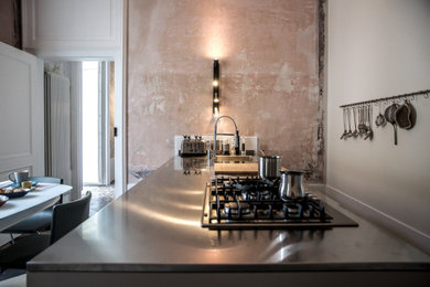 Idee per una cucina abitabile mediterranea con top in acciaio inossidabile, soffitto a volta, ante beige, pavimento in cementine e penisola