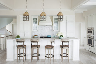 Inspiration for a large coastal l-shaped light wood floor and beige floor open concept kitchen remodel in Atlanta with recessed-panel cabinets, white cabinets, stainless steel appliances, an island, a farmhouse sink, marble countertops, white backsplash and glass tile backsplash