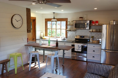 Example of a small farmhouse galley dark wood floor eat-in kitchen design in Phoenix with a double-bowl sink, beaded inset cabinets, white cabinets, quartzite countertops, white backsplash, ceramic backsplash, stainless steel appliances and a peninsula