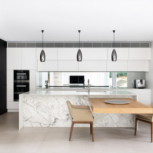 Design ideas for a large contemporary single-wall eat-in kitchen in Sydney with a double-bowl sink, white cabinets, solid surface benchtops, metallic splashback, mirror splashback, stainless steel appliances, cement tiles, multiple islands, grey floor and white benchtop.