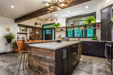 Inspiration for a large industrial l-shaped cement tile floor and gray floor kitchen pantry remodel in Manchester with an undermount sink, flat-panel cabinets, black cabinets, quartz countertops, white backsplash, porcelain backsplash, stainless steel appliances, an island and white countertops