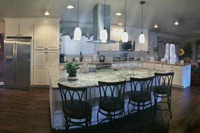 Open concept kitchen - large traditional l-shaped ceramic tile and brown floor open concept kitchen idea in Phoenix with an undermount sink, raised-panel cabinets, white cabinets, granite countertops, white backsplash, subway tile backsplash, stainless steel appliances and an island